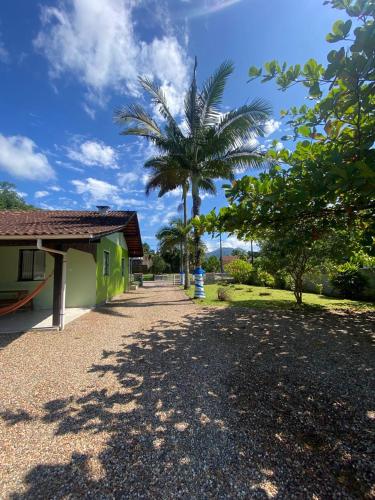 a house with a palm tree next to a road at Suites da Rota - Pomerode SC in Pomerode