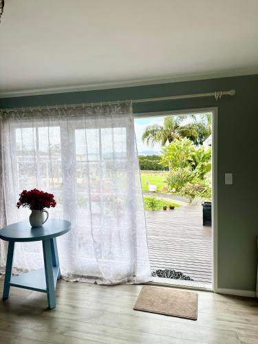 a room with a window with a table and a patio at Bycroft Lodge in Karaka