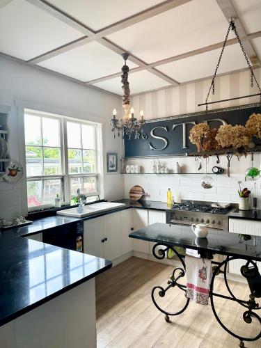 a large kitchen with black counter tops and a table at Bycroft Lodge in Karaka