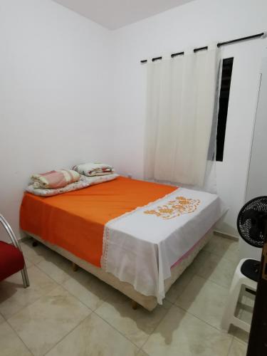 a bedroom with a bed with an orange and white blanket at Rancho do Poeta - Chalé Cajueiro in Lagoa Nova