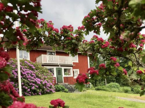 a red house with pink flowers in front of it at 6 person holiday home in LÖNASHULT in Lönashult