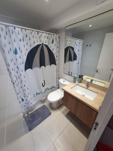 a bathroom with a toilet and a sink and a mirror at Departamento Laguna del Mar in La Serena