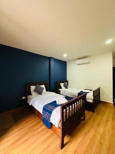 two beds in a room with blue walls and wooden floors at Zen NamKhan Riverside in Luang Prabang