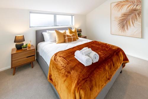 a bedroom with a large bed with towels on it at Modern 6BD Homes Carpark Avebury Park Avon River in Christchurch