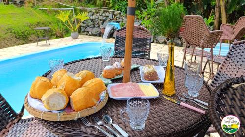 a table with a tray of bread and a bottle of wine at Chalé com Piscina e Natureza Primavera Rosa in Penha