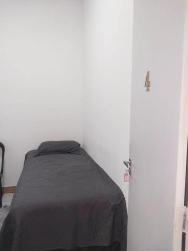 a bedroom with a bed and a white wall at Fênix hospedaria in Natal