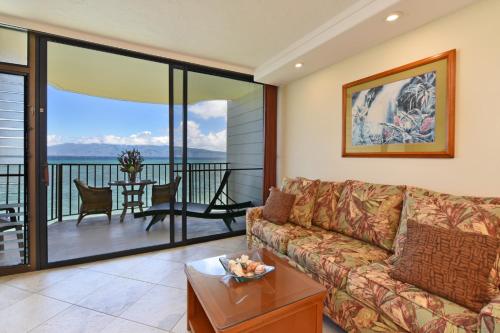 a living room with a couch and a balcony at Kahana Reef in Kahana