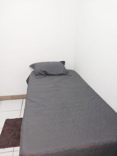 a bed with a gray comforter in a room at Fênix hospedaria in Natal