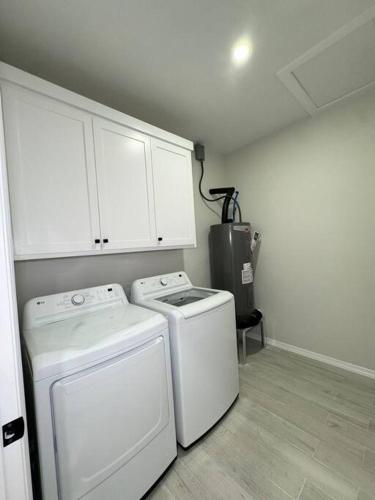 a kitchen with white cabinets and a washer and dryer at Welcome to Launchpad Living! in Brownsville