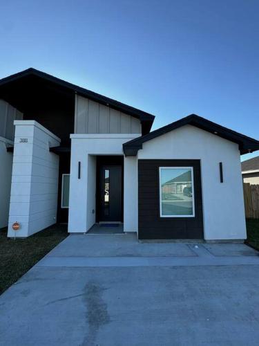 a white house with a black door and a driveway at Welcome to Launchpad Living! in Brownsville