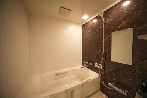 a bathroom with a bath tub and a mirror at Hub-Fun in Katsuno