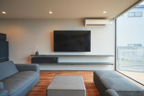 a living room with a couch and a flat screen tv at Hub-Fun in Katsuno