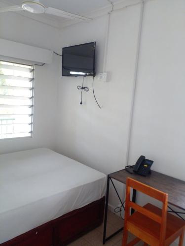a bedroom with a bed and a tv on the wall at Yatu Lau Transit Hotel in Nadi