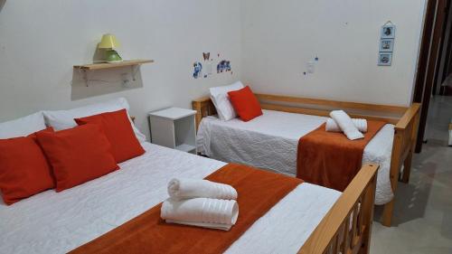 a bedroom with two beds with orange and white at Recanto do surf in Imbituba