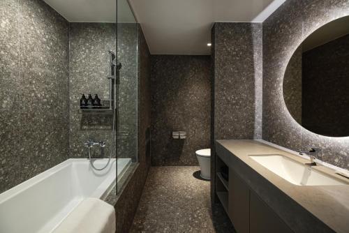 Un baño con bañera, lavabo e inodoro. en Kensington Resort Jeju Jungmun, en Seogwipo