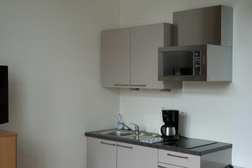a kitchen with a sink and a microwave at La Résidence de l'Orangerie in Strasbourg