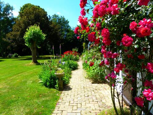 a garden with pink flowers on a brick path at Le Petit Verger in Grumesnil