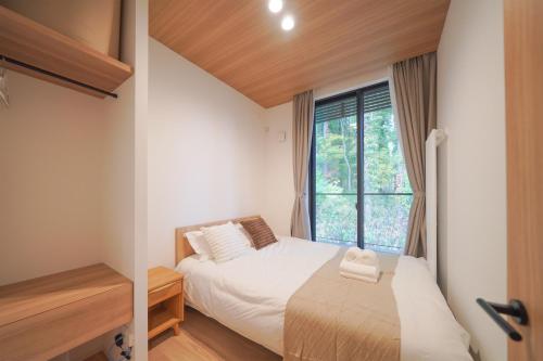 a small bedroom with a bed and a window at Queens Park CK Village Niseko Hirafu in Kutchan