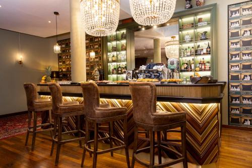 a bar in a restaurant with chairs and chandeliers at Hotel Indigo Turin by IHG in Turin