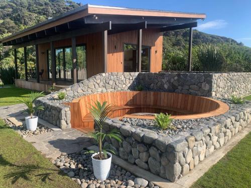 a stone retaining wall with a fire pit in front of a house at Te Whaanga Retreat & Spa in Raglan