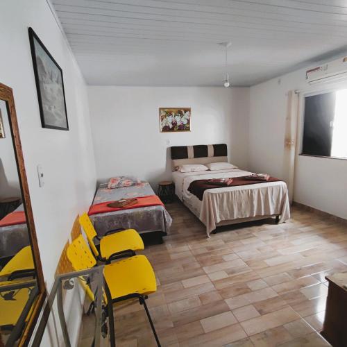 a bedroom with two beds and yellow chairs in it at Pousada Solar Encanto do Marajó in Soure