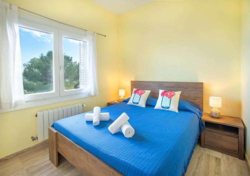 a bedroom with a blue bed with pillows and a window at Mar Bona in Tamariu