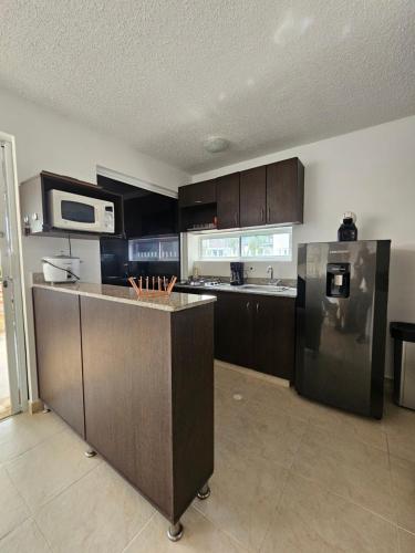 a kitchen with brown cabinets and a stainless steel refrigerator at Apartasol Ciudadela Santa Fé "El Refugio" in Santa Fe de Antioquia