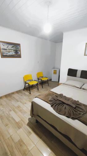 a bedroom with two beds and two yellow chairs at Pousada Solar Encanto do Marajó in Soure