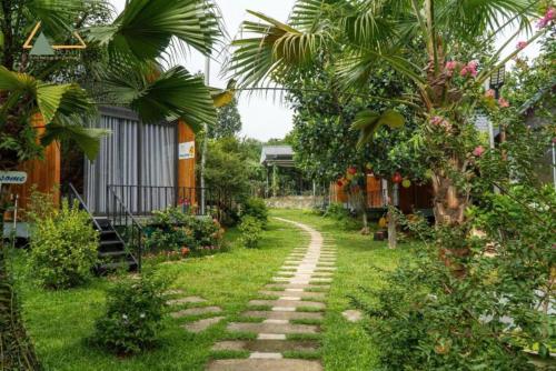a path through a garden with palm trees and plants at ST Homestay Tản Lĩnh - Venuestay in Mỹ Khê