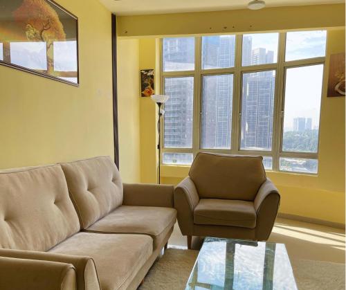 a living room with a couch and a chair and windows at Monkey Mansion in Kuala Lumpur