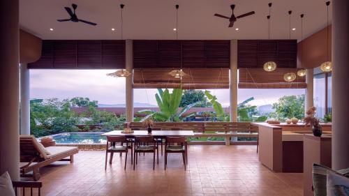 a dining room with a table and a large window at Amaya Kampot Homestays in Kampot