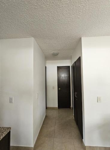 an empty hallway with a black door and a room at Apartasol Ciudadela Santa Fé "El Refugio" in Santa Fe de Antioquia