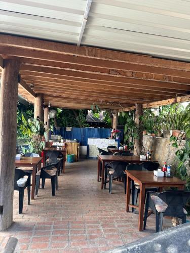 an outdoor patio with wooden tables and chairs at Zen NamKhan Riverside in Luang Prabang