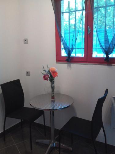 a table and two chairs and a vase with flowers at Dolce Casa in Sainte-Foy-lès-Lyon