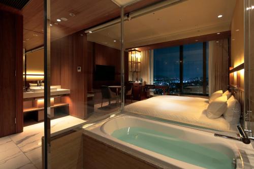 a bathroom with a tub and a bedroom with a bed at Candeo Hotels Osaka Hirakata in Hirakata
