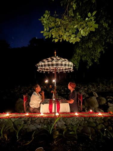 a group of people sitting at a table with an umbrella at Darmada Eco Resort in Sidemen