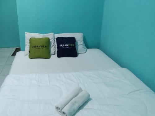 a white bed with two pillows on top of it at Urbanview Mitra Residence near Bandara Ahmad Yani Semarang in Kalibanteng-lor