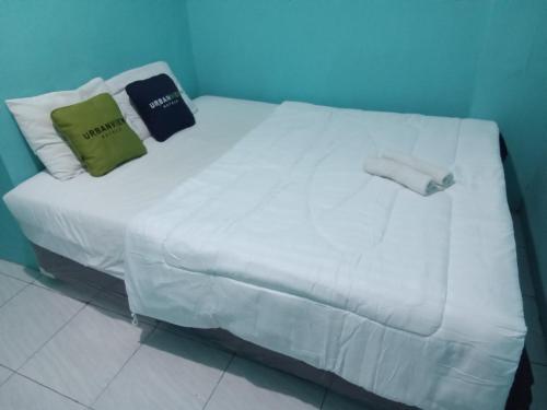 a white bed with two pillows on top of it at Urbanview Mitra Residence near Bandara Ahmad Yani Semarang in Kalibanteng-lor