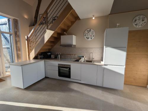 La cuisine blanche est équipée d'un évier et d'un réfrigérateur. dans l'établissement Maison de charme rénovée au cœur du Val de Loire avec parking et wifi inclus - FR-1-590-526, à Chaingy