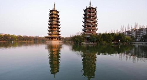 two towers sitting in the water next to a building at James Joyce Coffetel Guilin Railway Station Xiangbi Mountain Liangjiang Sihu Wharf in Guilin