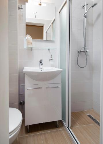 a white bathroom with a sink and a shower at La Perla Luxury Apartments in Split