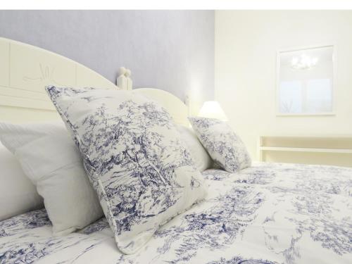 Cama con sábanas y almohadas azules y blancas en Pension Mayte, en Pamplona