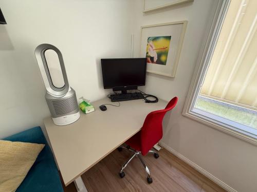 a desk with a computer monitor and a red chair at Private 1 bedroom apartment near beach and shops in Sydney