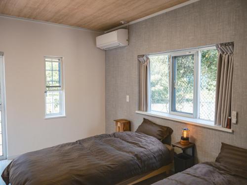 a bedroom with a bed and two windows at サードプレイス百島 in Onomichi