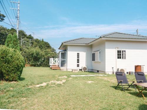 a white house with two chairs in the yard at サードプレイス百島 in Onomichi