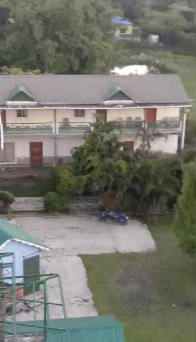 a large white house with a yard at Banolata Lakeside Homestay by StayApart in Damanpur