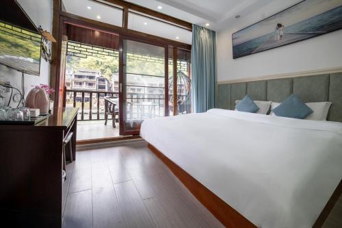 a bedroom with a large white bed and a balcony at Fenghuang Ancient Town Lazy Cat Riverside Inn in Fenghuang