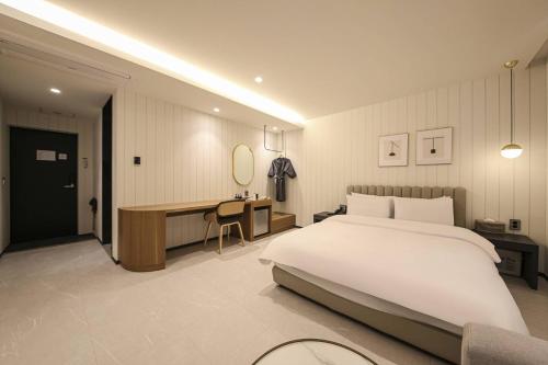 a bedroom with a large white bed and a desk at Browndot Hotel Deokjin in Jeonju