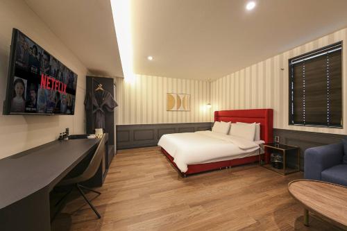 a bedroom with a bed and a table and a couch at Browndot Hotel Deokjin in Jeonju