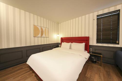 a bedroom with a large white bed and a window at Browndot Hotel Deokjin in Jeonju